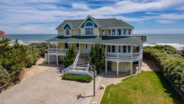 Ein zweistöckiges Haus mit Balkon, einer überdachten Veranda und Blick auf das Meer.