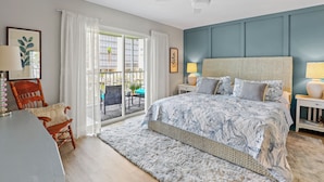 Une chambre avec un grand lit, une chaise, une table et une vue sur l’extérieur.