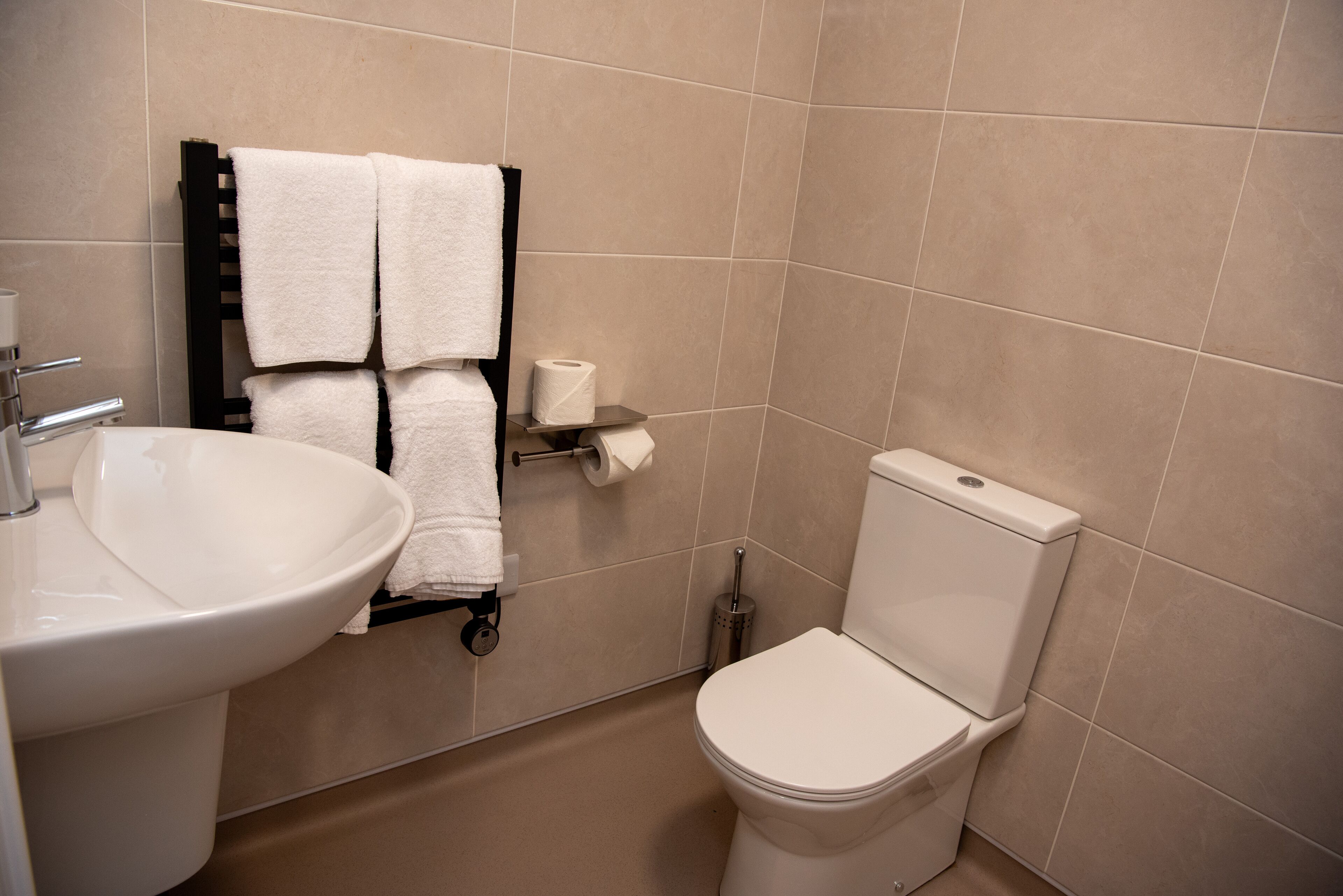 Un baño con lavamanos, inodoro y perchero para toallas.