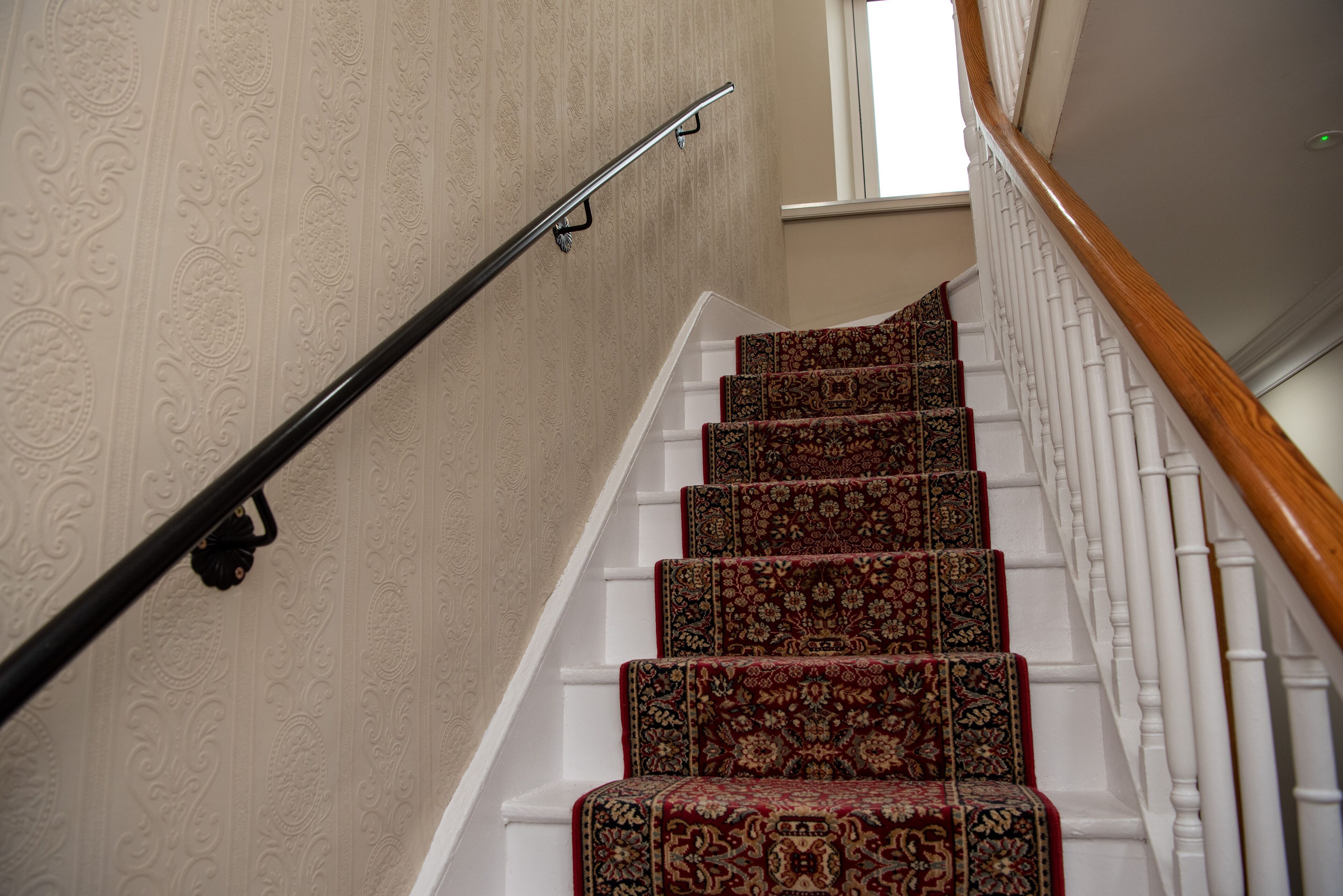 Eine Treppe mit aufwendiger, teppichbespannter Laufstufen und einem Geländer.