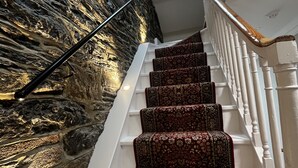 Un escalier recouvert d’une moquette à motifs menant à une pièce située au troisième étage.