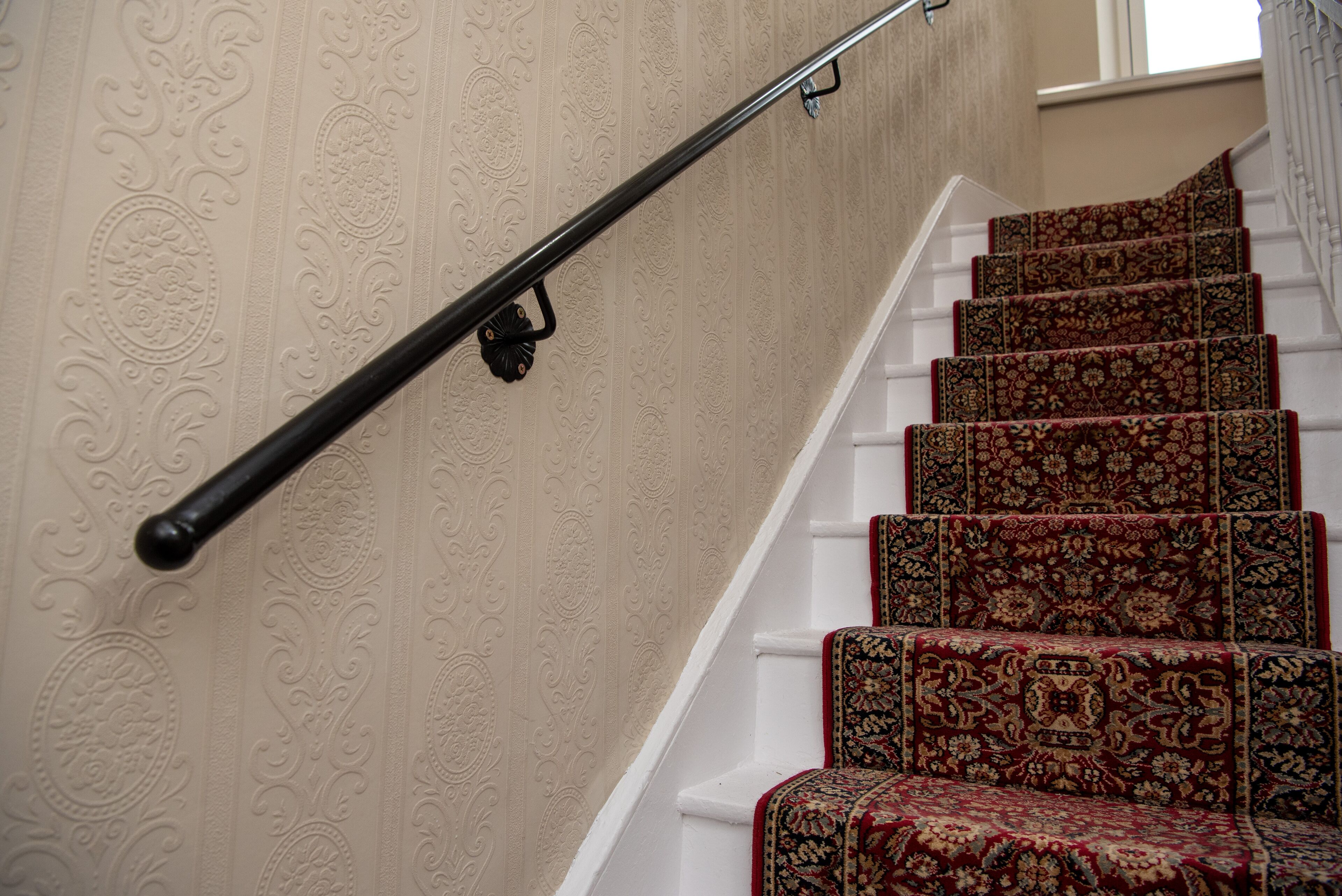 Una escalera con papel tapiz decorativo y alfombra estampada.