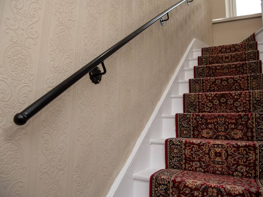 A staircase with ornate wallpaper and patterned carpet.