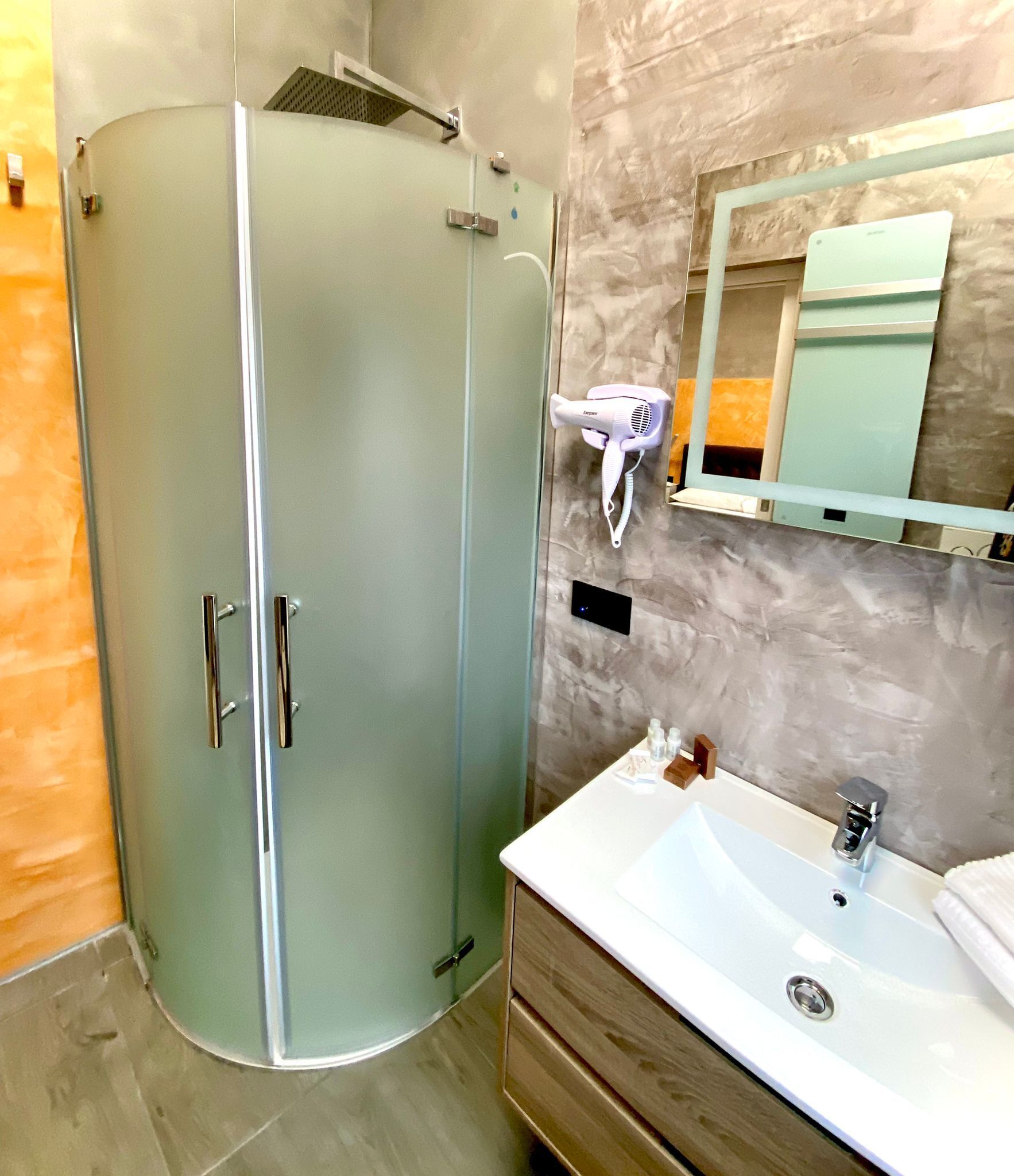 A bathroom with a glass-enclosed shower, a white sink, a mirror, and a towel rack.