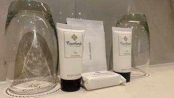 A collection of Coastlands Hotels & Resorts toiletries including body lotion, a sanitary bag, and luxury palm soap.