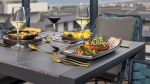 Una mesa de comedor con platos de comida, copas de vino y cubiertos.