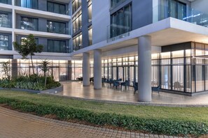 A modern hotel with a spacious outdoor seating area, large windows, and a well-maintained garden. - Coastlands Skye Hotel (Umhlanga)