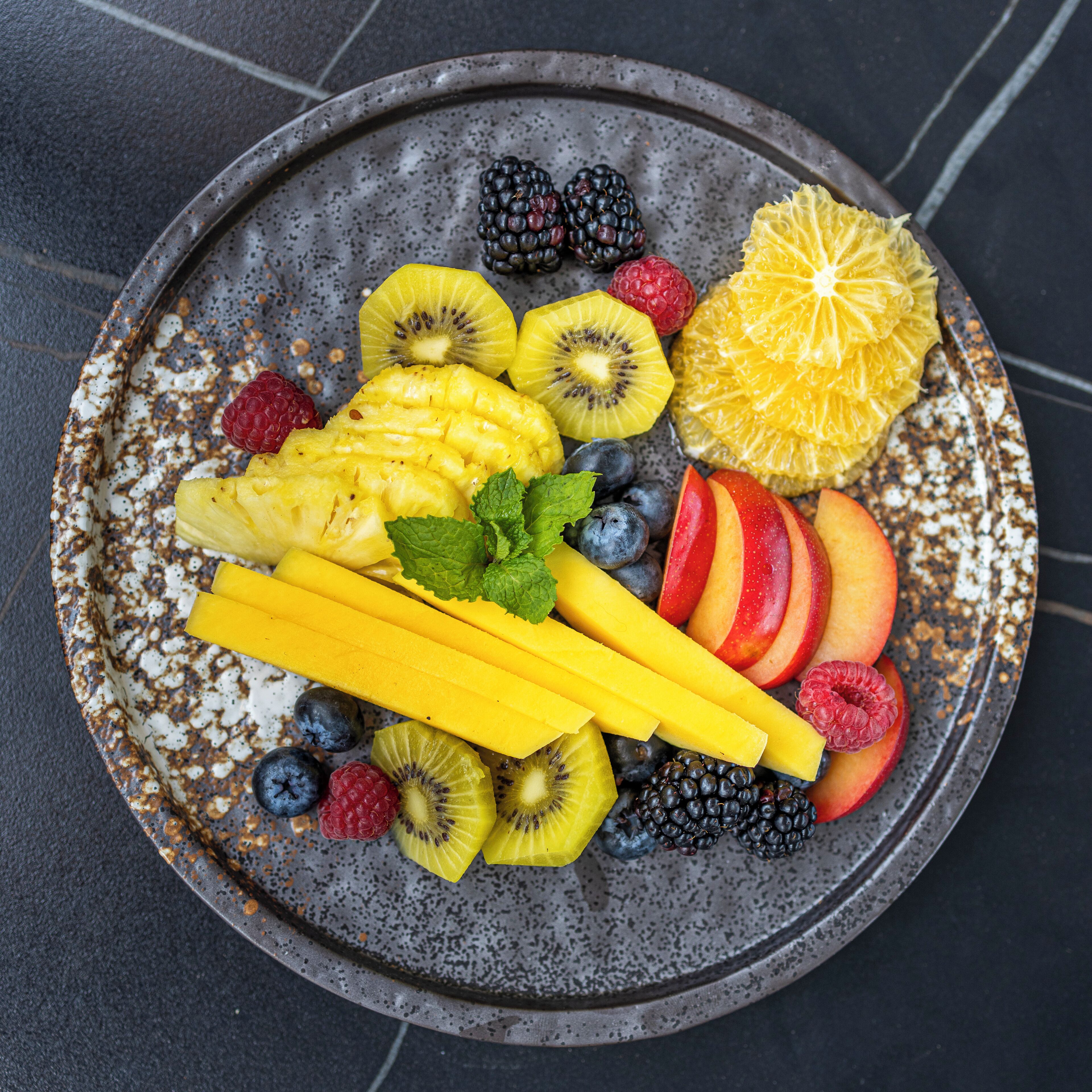 A fruit platter on a speckled ceramic plate.