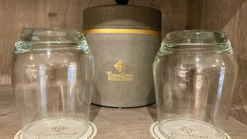 Two clear glass jars with lids, each on a white coaster with 'Coastlands Hotels & Resorts' branding, placed on a wooden surface with a grey container in the background.