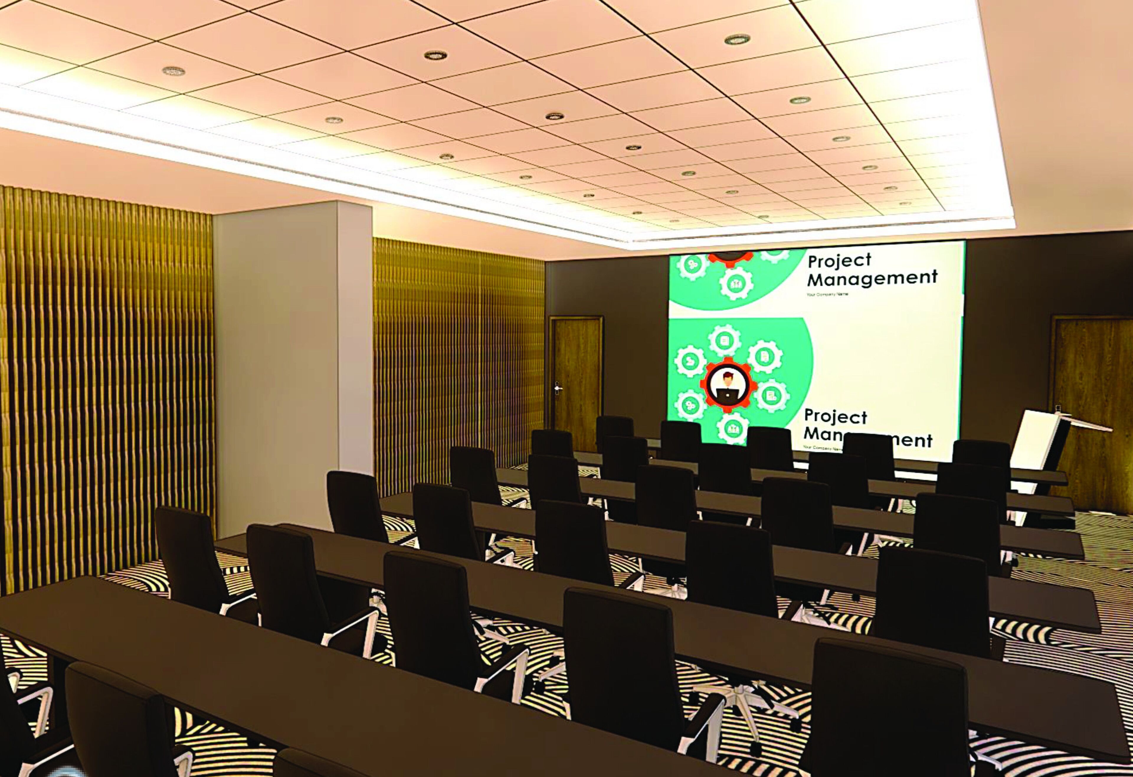A conference room with rows of chairs, a projector screen displaying 'Project Management', and a patterned carpet.