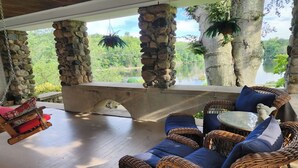 Un espace extérieur aménagé, abrité et doté de mobilier en osier et d’un mur en pierre.