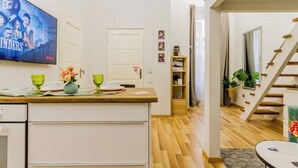 A modern kitchen with a wooden countertop, a television mounted above it, and a staircase leading to an upper floor. - W17Cozy in the Inner city, Cleaned by the Owner (Budapest)