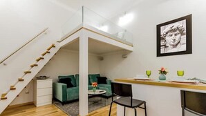 A compact living space with a loft bedroom, a dining area, and a seating area with a green sofa and a coffee table. - W17Cozy in the Inner city, Cleaned by the Owner (Budapest)