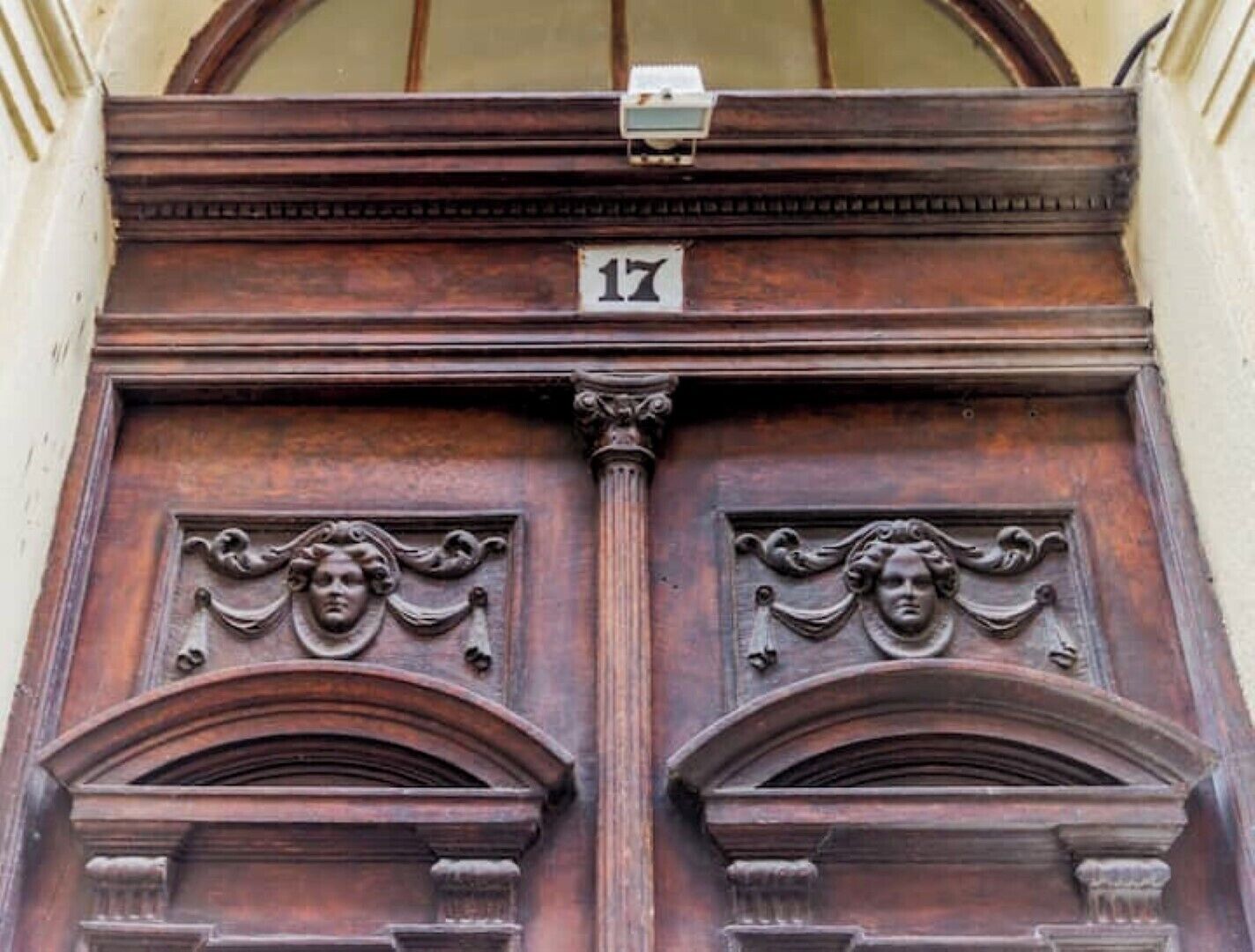 A wooden door with a number plaque, flanked by ornate carvings and a classical architectural style.