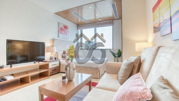 Ein modernes Wohnzimmer mit Flachbildfernseher, Couchtisch aus Holz, beiger Couch und großem Fenster mit Blick auf die Stadt.