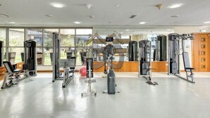 Ein Fitnessstudio mit verschiedenen Trainingsgeräten, großen Fenstern und einem modernen, sauberen Innenraum.