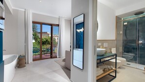 A modern bathroom with a bathtub, a glass shower enclosure, and a large mirror. - Estate4home - Suites 21 (Sorrento)
