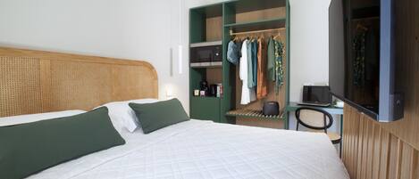Una habitación de hotel moderna con una cama grande, un armario, un escritorio y un televisor.
