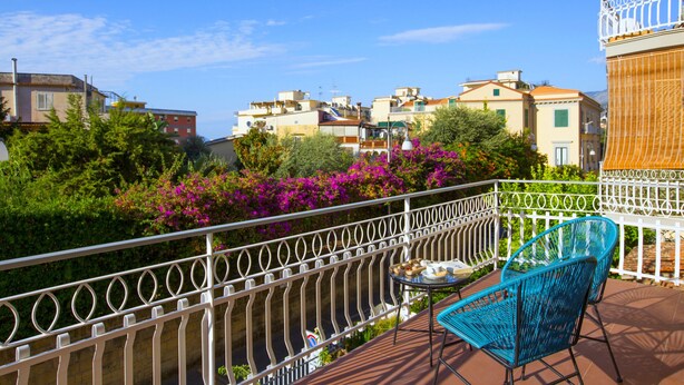 A balcony with a view of a river, surrounded by buildings and lush greenery. - Estate4home - Suites 21 (Sorrento)