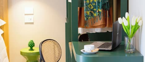 Une petite pièce moderne, équipée d’un bureau, d’une chaise, d’un ordinateur portable et d’un portant à vêtements.