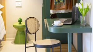 A compact room with a desk, chair, laptop, and a small table with a cup and cookies. - Estate4home - Suites 21 (Sorrento)