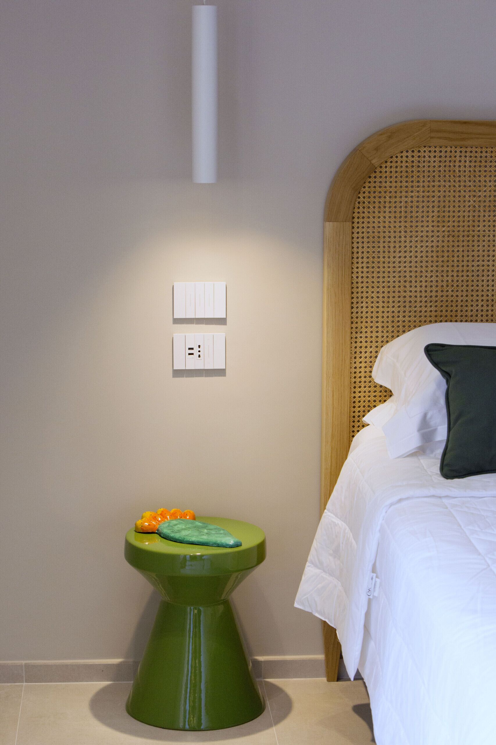 Una habitación con una cama, un inodoro verde y una lámpara fijada a la pared.