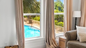 A room with a view of a swimming pool, a sofa, a lamp, and a small table. - Seaview Villas by Panhandle Getaways (Santa Rosa Beach)