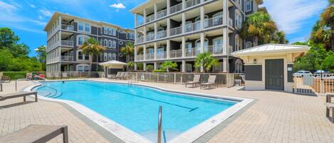 A multi-story hotel with a swimming pool, outdoor seating, and a covered area.