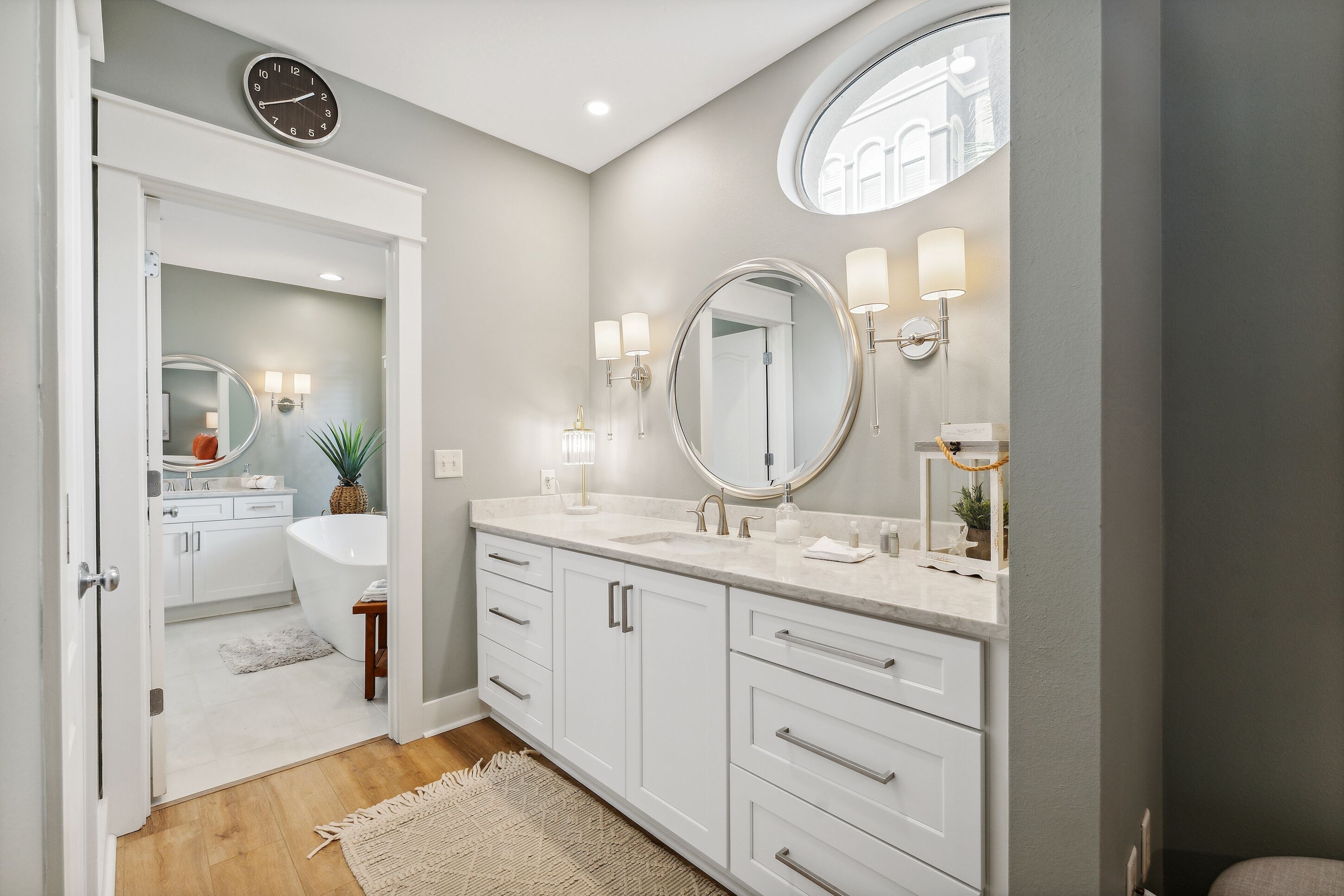 A modern bathroom with a freestanding bathtub, a large mirror, and a vanity with a sink.