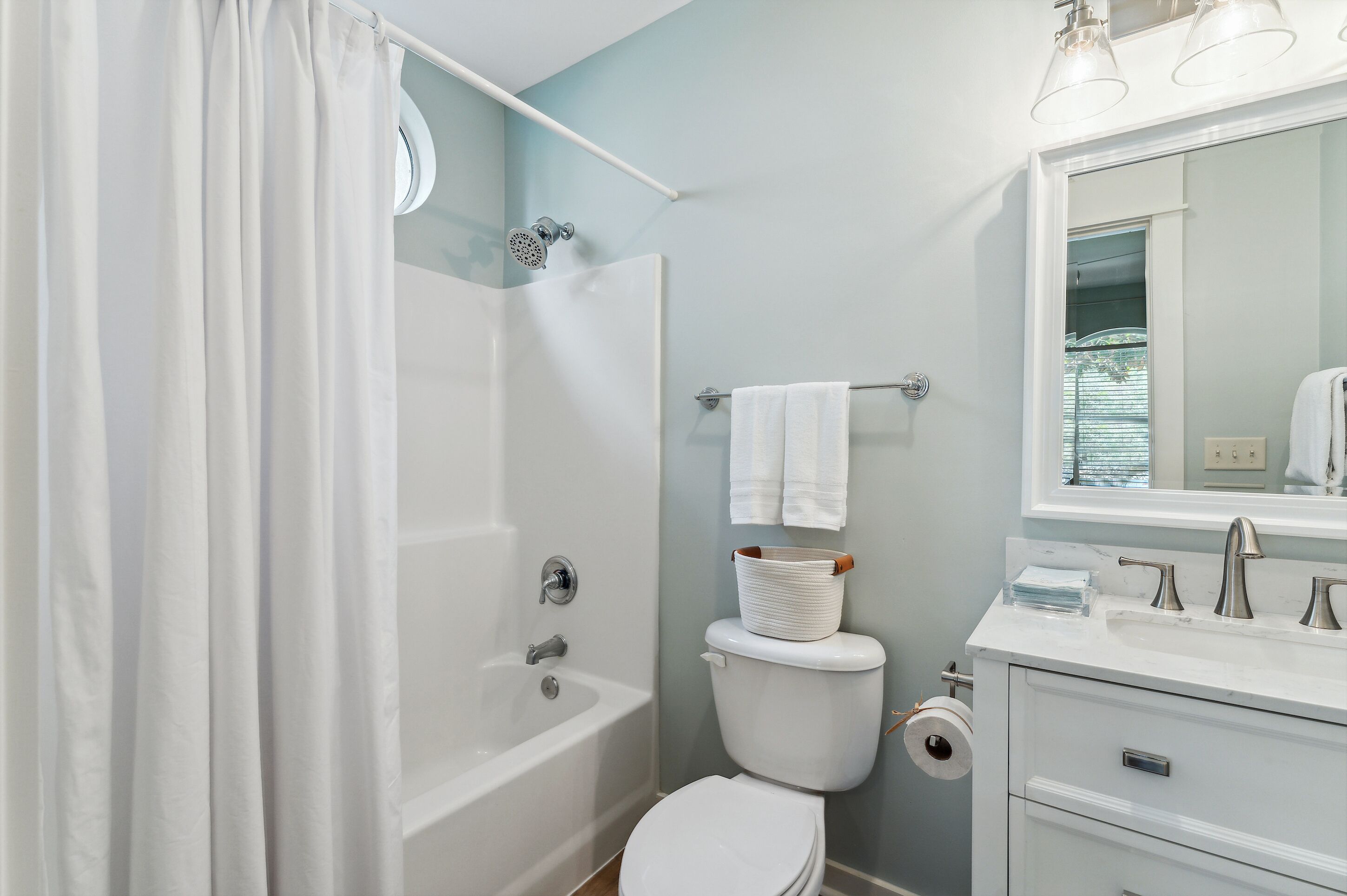 A bathroom with a bathtub, toilet, sink, and a mirror.