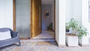 Un ingresso che dà su un corridoio con una pianta in vaso e un'opera d'arte astratta appesa al muro.