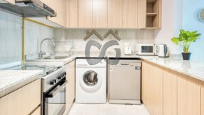 A compact kitchen with a stove, microwave, washing machine, and dishwasher. - Serene 2 Bedroom Apartment in Dubai Silicon Oasis (دبي)
