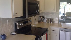 A kitchen with white cabinets, a microwave, an oven, a coffee maker, and a dishwasher. - It is at the heart of Naples. Minutes from beach. Condo w/ pools, tennis, golf.  (Naples)