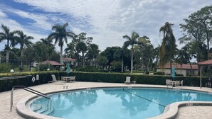 A swimming pool with a tiled deck, surrounded by palm trees and a gazebo. - It is at the heart of Naples. Minutes from beach. Condo w/ pools, tennis, golf.  (Naples)