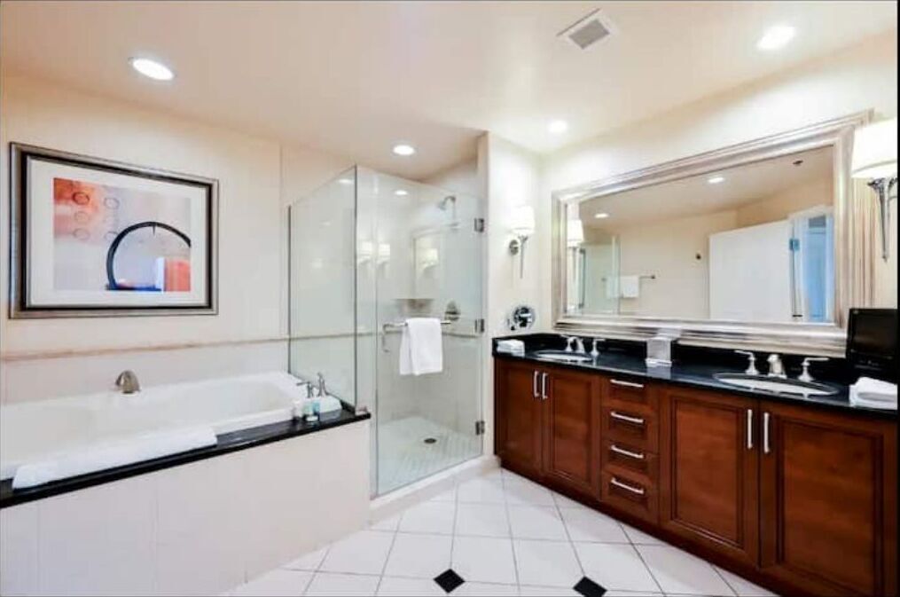 Un baño moderno con cabina de ducha de vidrio, un espejo grande y un mueble de tocador doble.