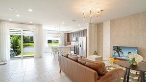 A modern living room with a sofa, a dining table, and a kitchen area in the background. - Stunning Brand New 3 Bedroom, 2.5 Bathroom Luxury Townhome with Loft. (Deerfield Beach)
