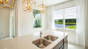 A kitchen with a large island, stainless steel sink, and pendant lights. - Stunning Brand New 3 Bedroom, 2.5 Bathroom Luxury Townhome with Loft. (Deerfield Beach)