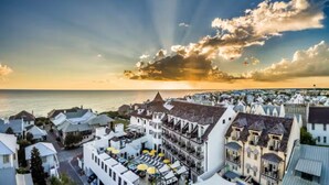 A coastal town with a prominent building featuring a balcony and outdoor seating, overlooking the sea.