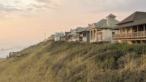 A coastal property with multiple houses on a grassy hill overlooking the beach.