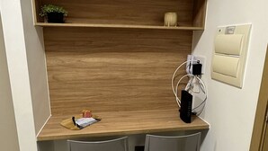 Une petite cuisine équipée avec un plan de travail en bois, deux chaises, une petite étagère avec une plante et une machine à café.