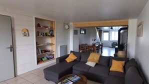 Een woonkamer met een donkere bank, een salontafel en een boekenplank.