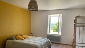 Een slaapkamer met een bed, een raam met uitzicht en een houten vloer.