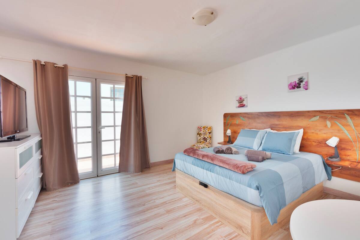 Quarto com cama, televisão e porta de vidro deslizante.