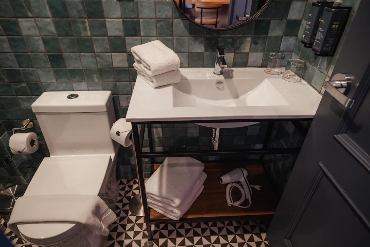 A bathroom with a toilet, sink, and towel stack.