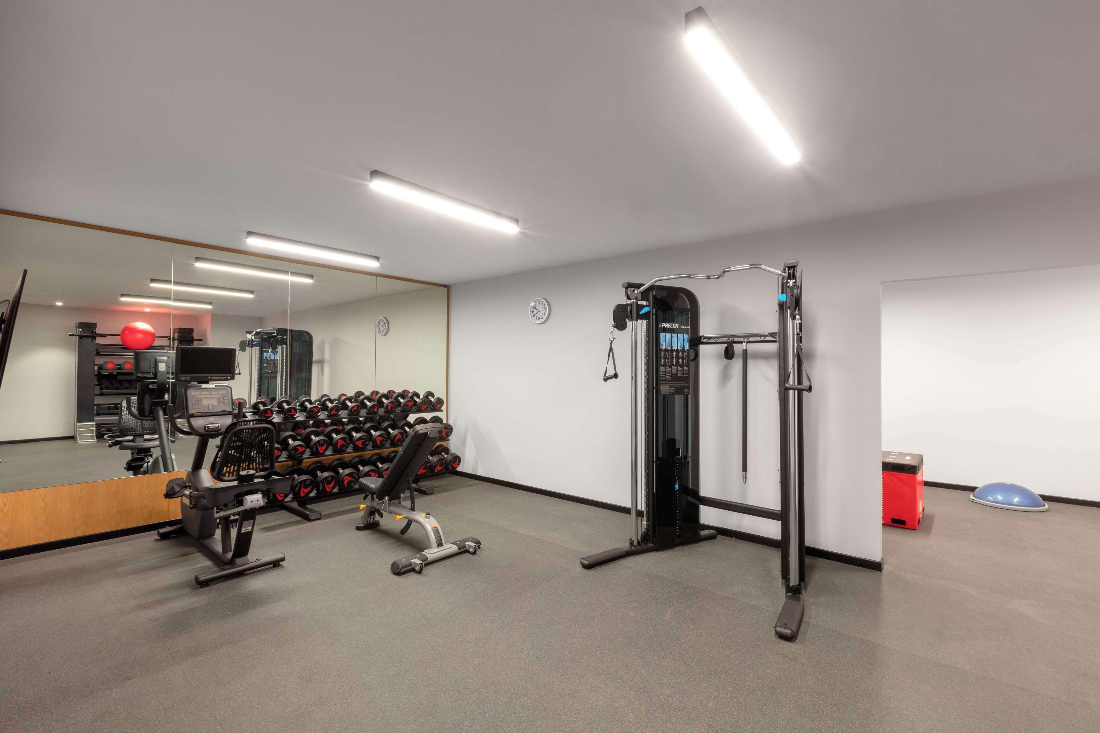 Un gimnasio con equipo de ejercicio, un espejo y un reloj en la pared.