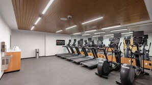 Un gimnasio con cintas de correr, elípticas y bicicletas estáticas, con un letrero de Hilton Garden Inn.