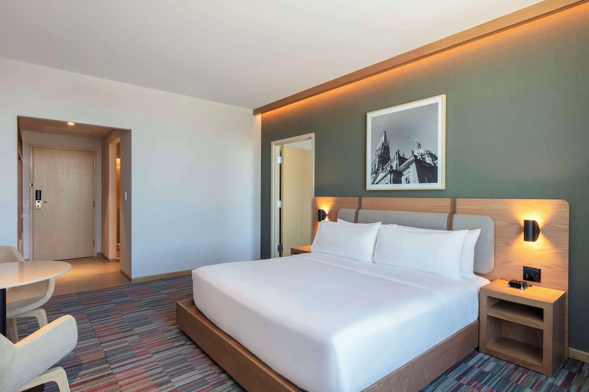 Une chambre d’hôtel avec un grand lit, des tables de chevet, un bureau et une chaise.