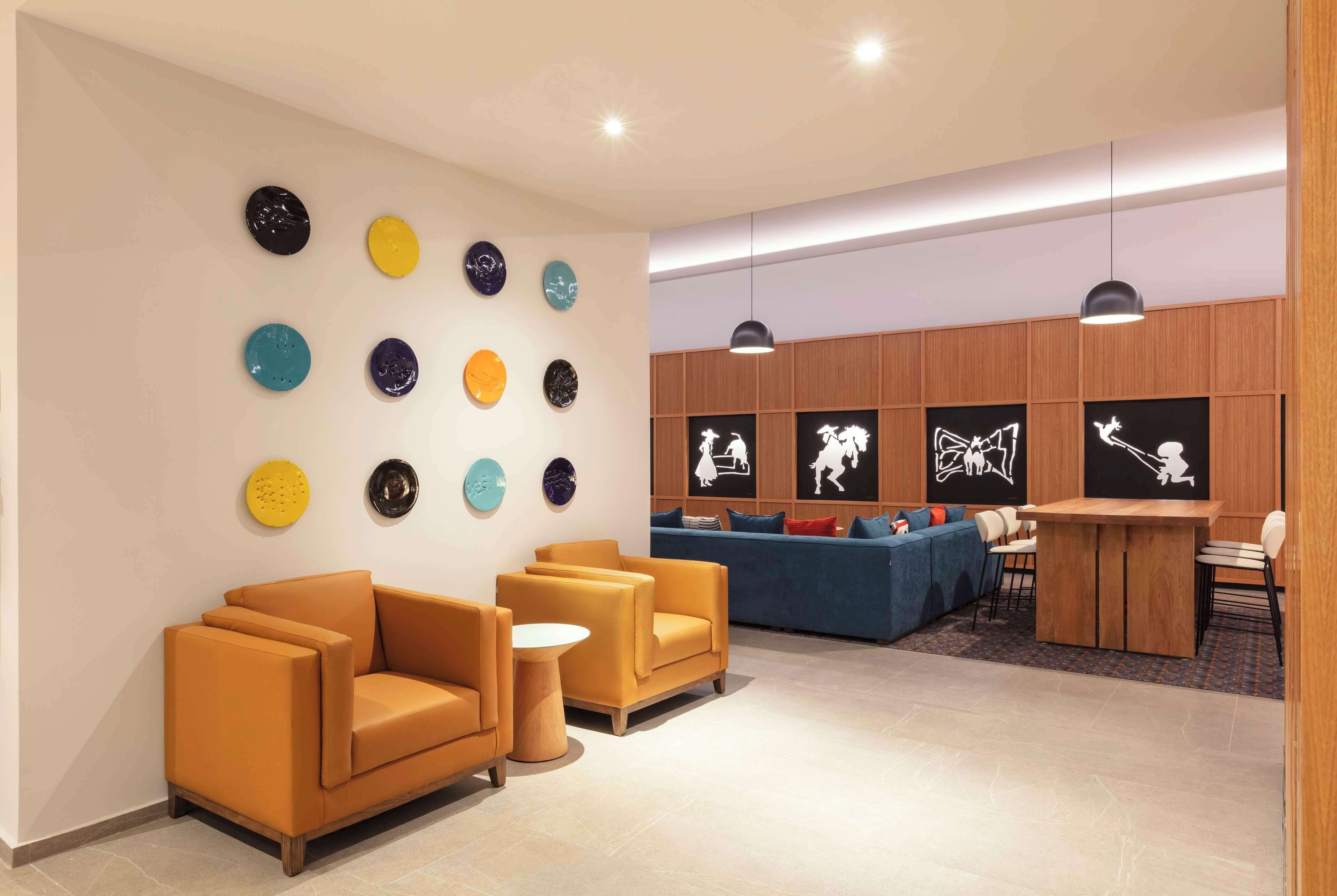 Een moderne lobby met een bank, stoelen, een kleine tafel en wanddecoratie.