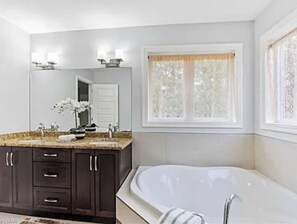 A modern bathroom with a freestanding bathtub, dark wooden cabinets, a granite countertop, and a large mirror. - Pookah Bill House! (London)
