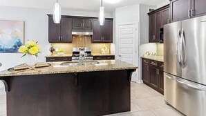 A modern kitchen with dark wooden cabinets, stainless steel appliances, and a central island with a sink. - Pookah Bill House! (London)